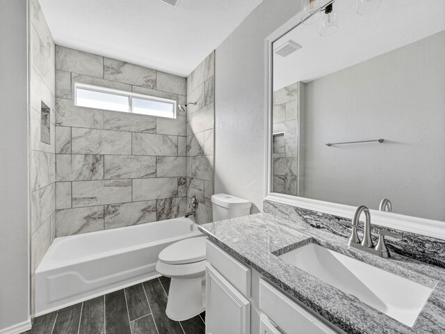 full bathroom featuring vanity, tiled shower / bath combo, and toilet