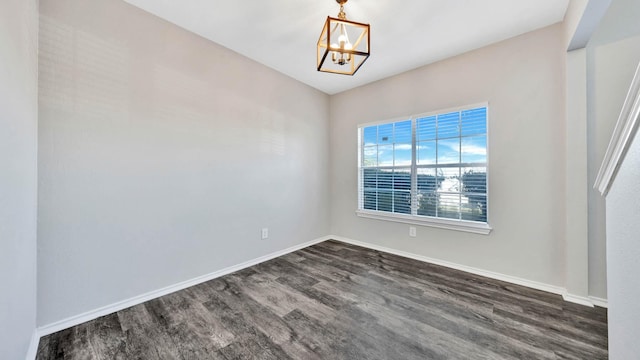 unfurnished room featuring dark wood-type flooring and an inviting chandelier