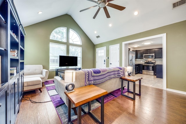 living room featuring ceiling fan, light wood-type flooring, and lofted ceiling