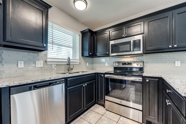 kitchen with tasteful backsplash, sink, light tile patterned flooring, and appliances with stainless steel finishes