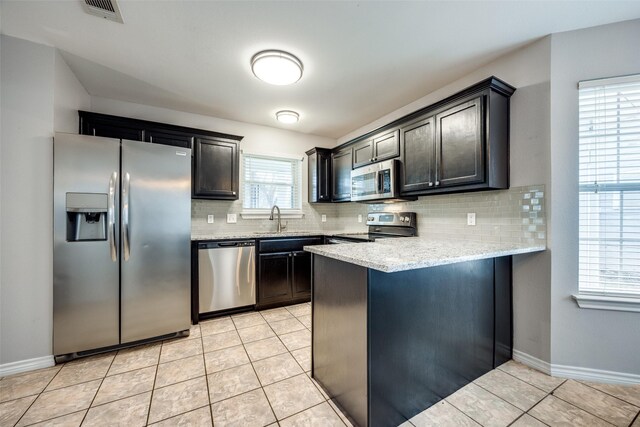 kitchen featuring backsplash, sink, light tile patterned floors, and stainless steel appliances