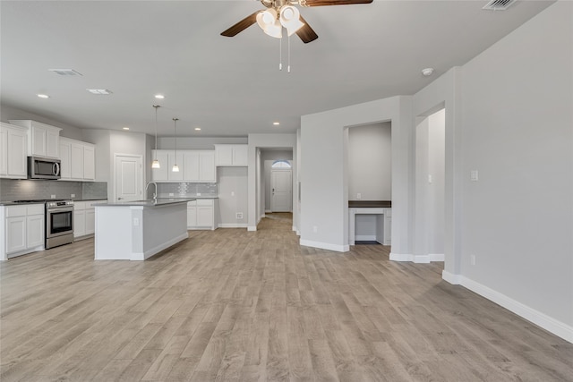 kitchen with pendant lighting, a center island with sink, appliances with stainless steel finishes, tasteful backsplash, and white cabinetry