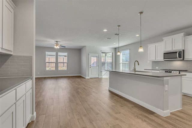 kitchen featuring white cabinets, ceiling fan, sink, and an island with sink