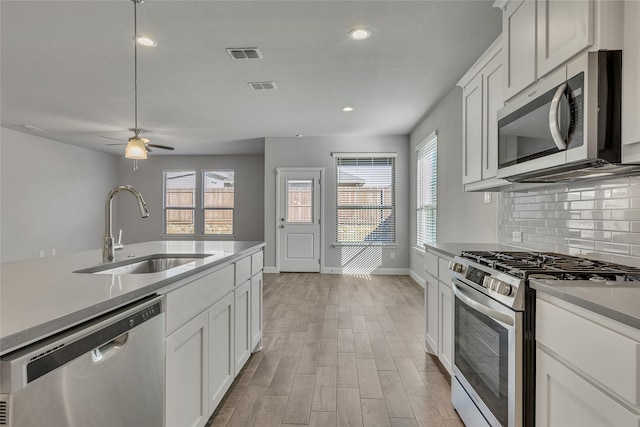 kitchen featuring white cabinetry, sink, backsplash, light hardwood / wood-style floors, and appliances with stainless steel finishes