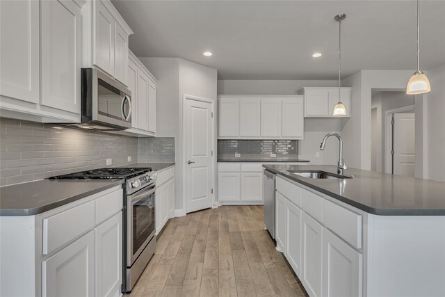 kitchen with white cabinets, appliances with stainless steel finishes, decorative light fixtures, and sink