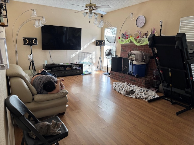 living room with light wood-type flooring, a textured ceiling, and ceiling fan