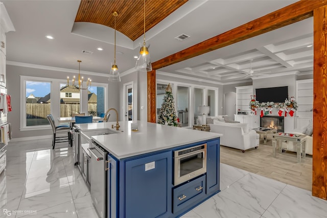 kitchen with blue cabinetry, coffered ceiling, decorative light fixtures, and an island with sink