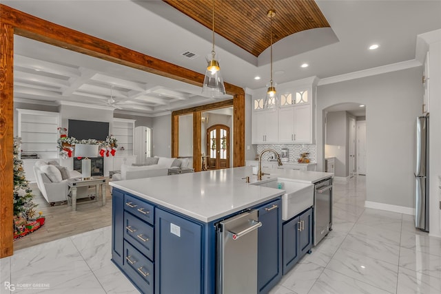 kitchen featuring pendant lighting, white cabinetry, an island with sink, stainless steel appliances, and blue cabinetry