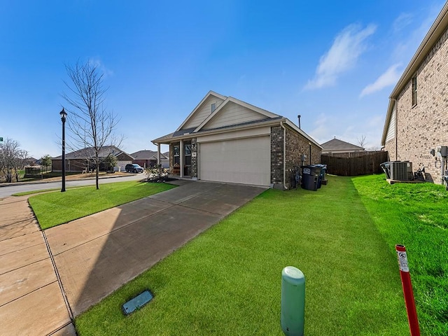 view of front of home featuring a garage, a front yard, and central AC