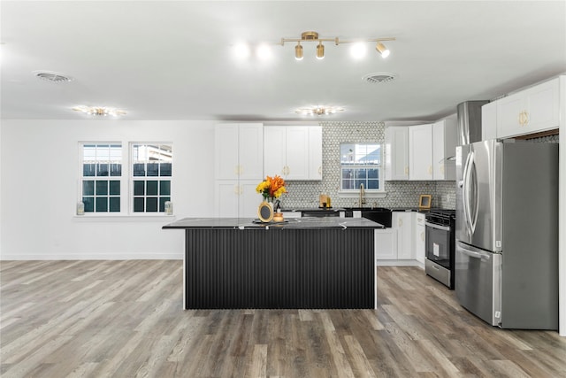 kitchen featuring decorative backsplash, white cabinetry, a kitchen island, and stainless steel appliances