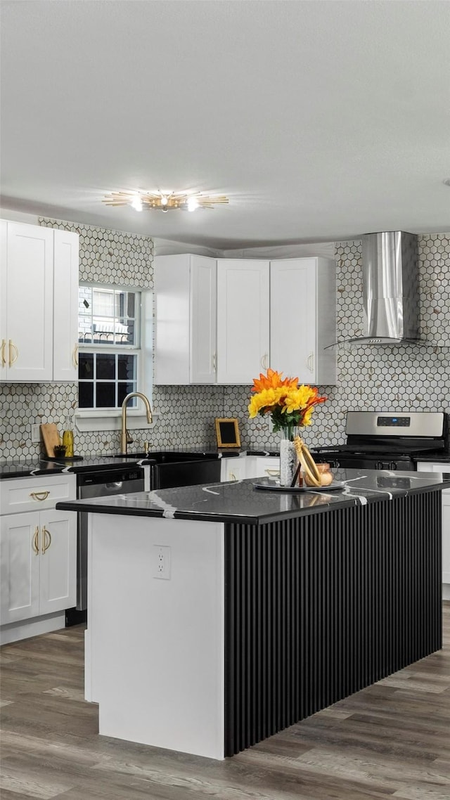 kitchen featuring white cabinets, appliances with stainless steel finishes, a center island, and wall chimney exhaust hood