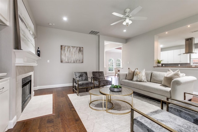 living room with dark wood-type flooring, ceiling fan, and a fireplace