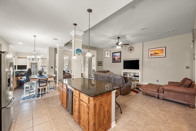 kitchen with a kitchen bar, stainless steel fridge, ceiling fan with notable chandelier, and decorative light fixtures