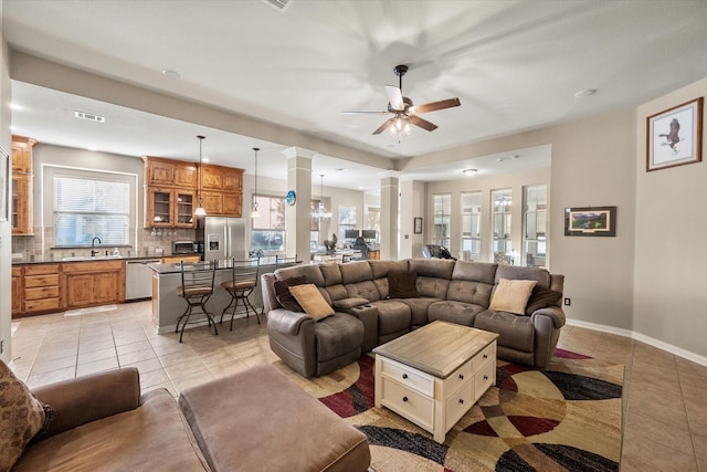 living room with decorative columns, ceiling fan, sink, and light tile patterned floors