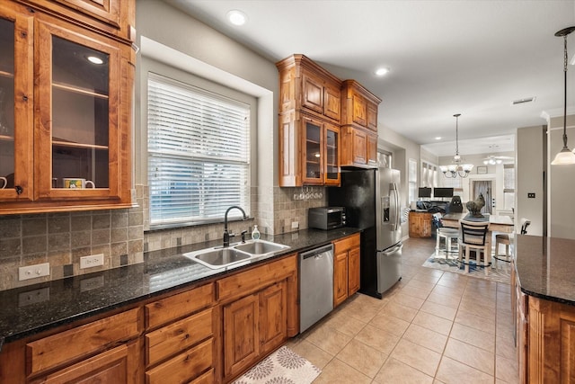 kitchen featuring light tile patterned flooring, sink, dark stone countertops, appliances with stainless steel finishes, and pendant lighting