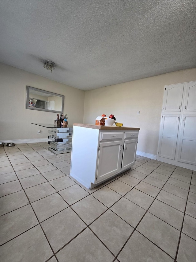 kitchen featuring light tile patterned floors, white cabinets, and a textured ceiling