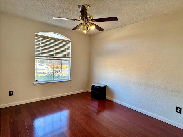 spare room featuring dark hardwood / wood-style floors, ceiling fan, and a textured ceiling