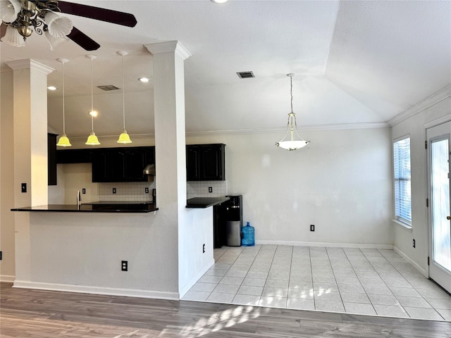 kitchen with backsplash, vaulted ceiling, ceiling fan, ornamental molding, and light tile patterned flooring