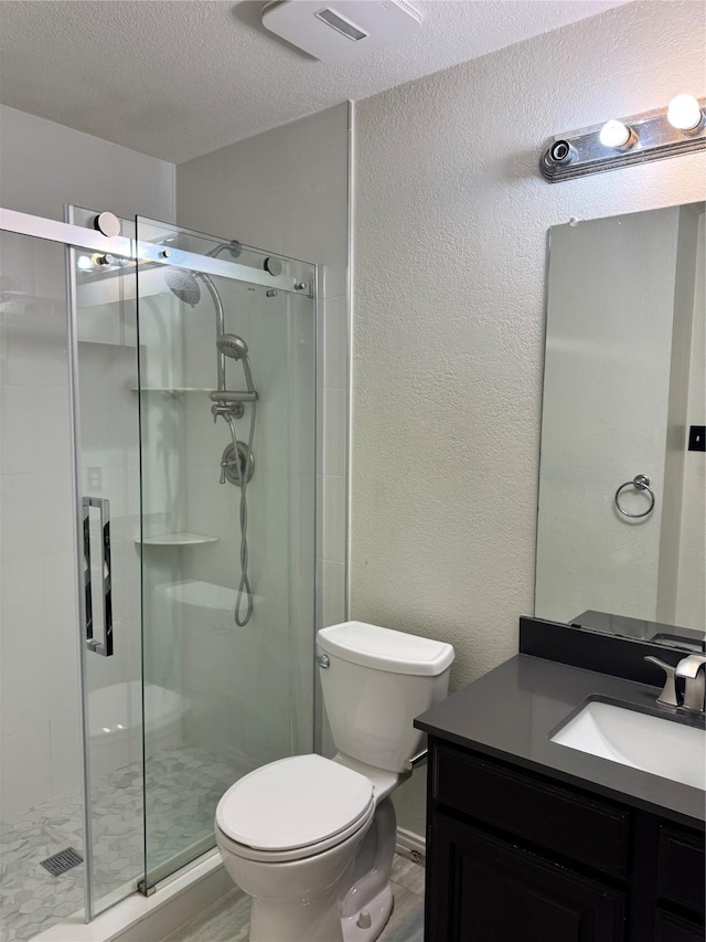 bathroom featuring vanity, a textured ceiling, toilet, and a shower with door