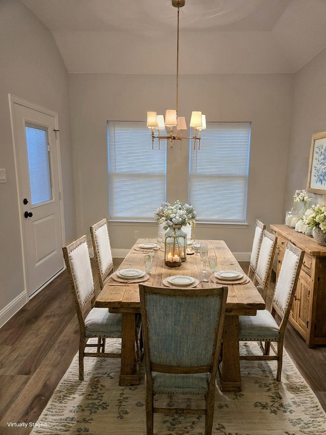 dining space with dark hardwood / wood-style floors, vaulted ceiling, plenty of natural light, and a notable chandelier