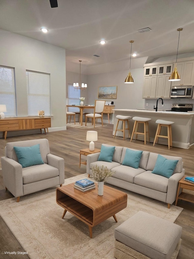 living room featuring hardwood / wood-style flooring, a notable chandelier, and sink