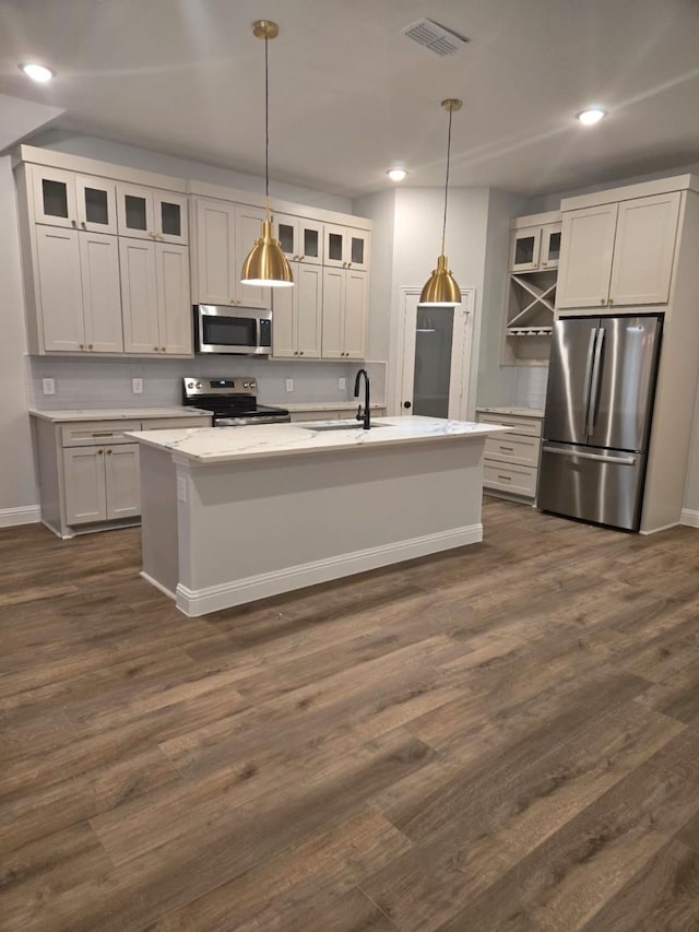 kitchen with stainless steel appliances, pendant lighting, sink, and a center island with sink