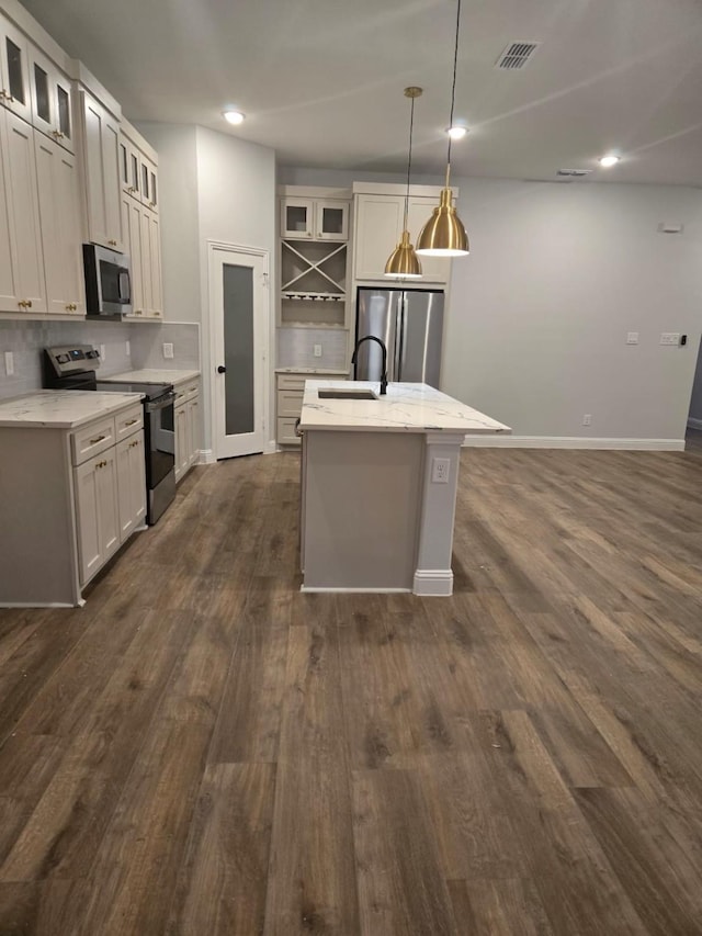 kitchen featuring stainless steel appliances, decorative light fixtures, a kitchen island with sink, and white cabinets