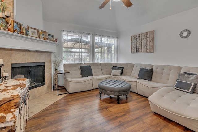 living area featuring lofted ceiling, a tile fireplace, wood finished floors, and a ceiling fan