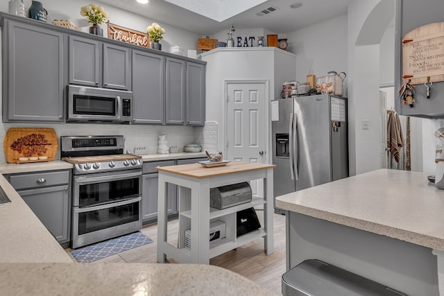 kitchen with light countertops, appliances with stainless steel finishes, visible vents, and gray cabinetry