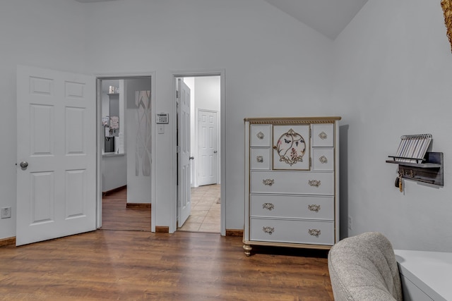 bedroom featuring lofted ceiling, baseboards, and wood finished floors