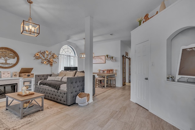 living area with lofted ceiling, a barn door, a glass covered fireplace, and visible vents