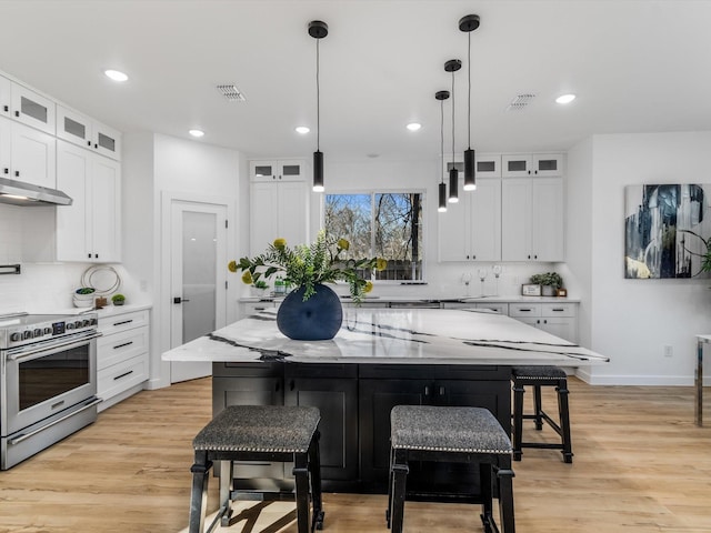 kitchen with white cabinets, a breakfast bar, electric range, and a center island