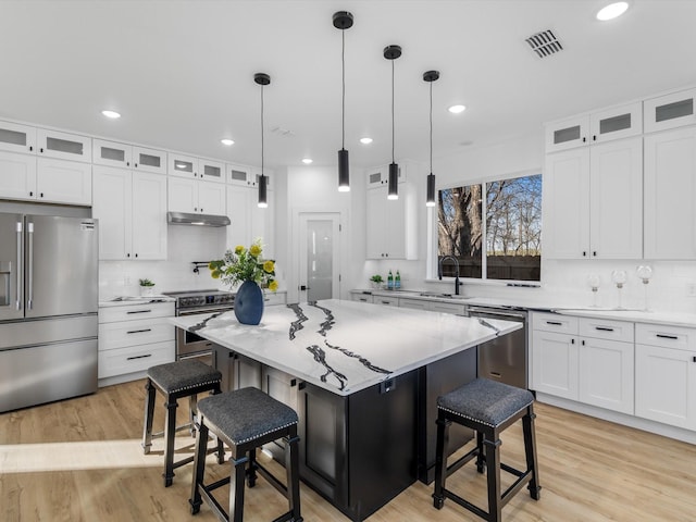 kitchen with high end appliances, a breakfast bar area, a kitchen island, and white cabinetry