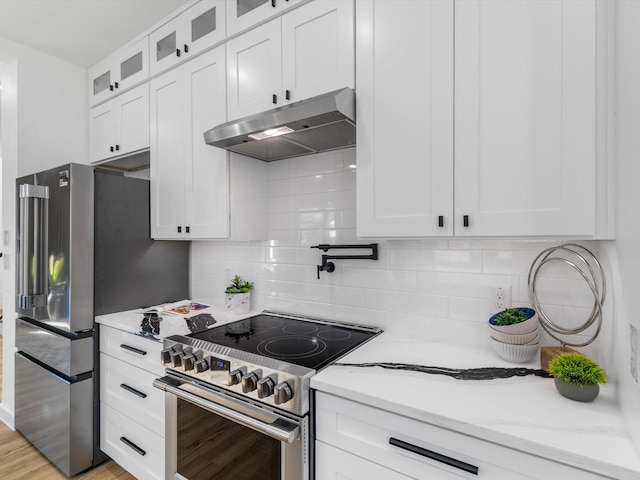 kitchen with light stone countertops, white cabinets, backsplash, and appliances with stainless steel finishes