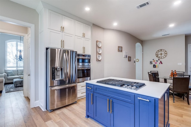 kitchen with white cabinets, appliances with stainless steel finishes, a center island, and blue cabinets