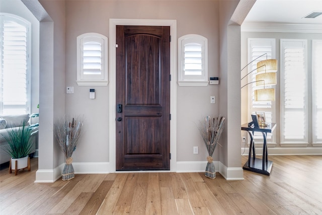 foyer with light hardwood / wood-style floors, a wealth of natural light, and crown molding