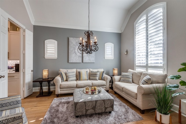 living room with a chandelier, ornamental molding, light hardwood / wood-style flooring, and lofted ceiling