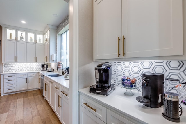 kitchen with backsplash, sink, white cabinets, and stainless steel dishwasher