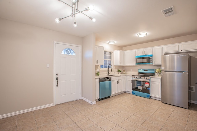 kitchen featuring appliances with stainless steel finishes, white cabinetry, a notable chandelier, and sink