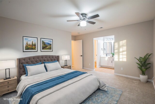 bedroom with ensuite bathroom, ceiling fan, and light colored carpet