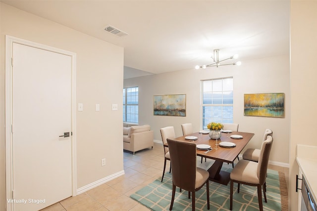 dining area with a notable chandelier, light tile patterned flooring, and a wealth of natural light