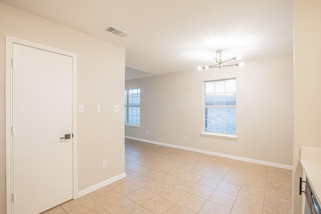 spare room featuring a notable chandelier and light tile patterned flooring