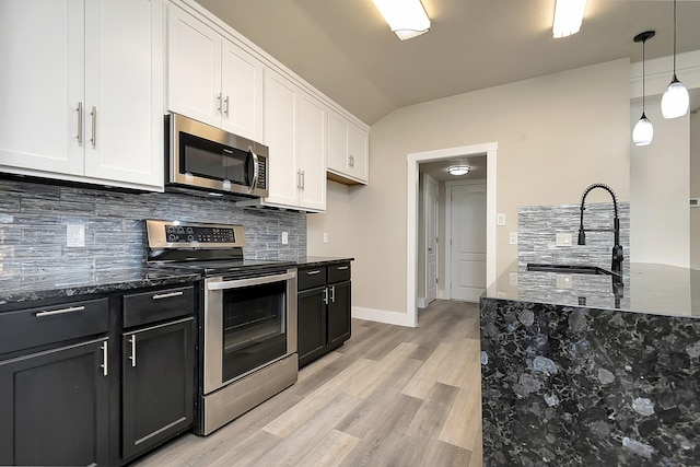 kitchen featuring lofted ceiling, white cabinets, hanging light fixtures, sink, and appliances with stainless steel finishes