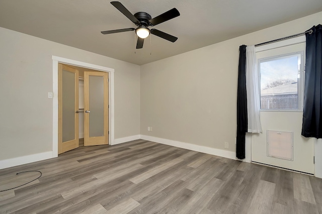 spare room with baseboards, ceiling fan, and light wood finished floors