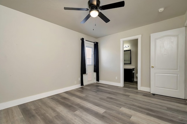 unfurnished bedroom featuring light wood-type flooring, ensuite bathroom, and ceiling fan