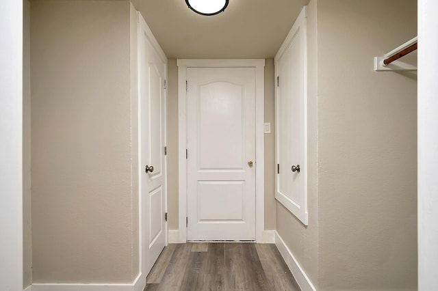 corridor featuring dark wood finished floors and baseboards