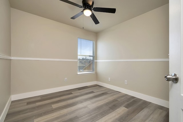 empty room with ceiling fan, wood finished floors, and baseboards