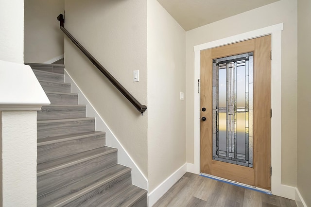 foyer entrance with stairway, baseboards, and wood finished floors