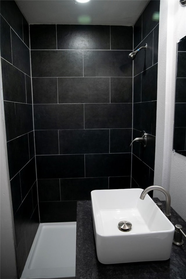 bathroom featuring tiled shower and sink