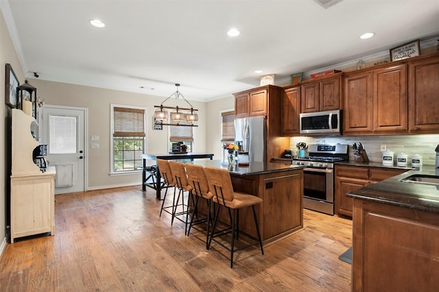 kitchen with backsplash, crown molding, pendant lighting, and stainless steel appliances